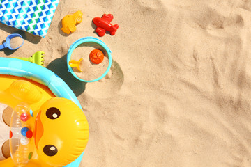 Flat lay composition with plastic beach toys and inflatable duck on sand. Space for text