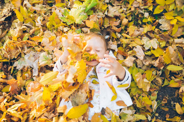 little toddler girl laying on the ground in yellow leaves