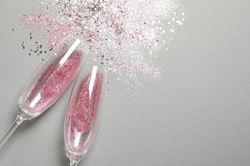 Flat lay composition with champagne glasses for celebration on grey background. Space for text