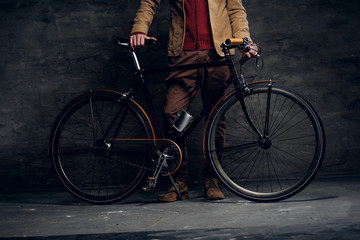 Man with his bicycle is posing for photographer at dark photo studio.