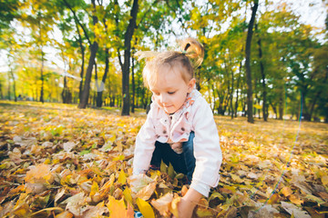 little smiling blond cute toddler girl at autumn city park