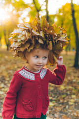 little toddler girl playing with maple leaves wreath