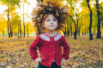 little toddler girl playing with maple leaves wreath