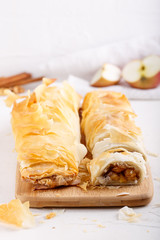 Apple strudel on white table. Homemade pie with apples, walnuts and cinnamon.