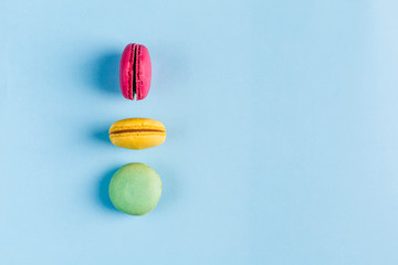 Multicolored macaroons on a blue background, top view, Flatley with copy space