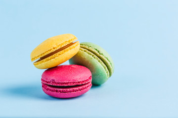 Colorful macaroons on a blue background, close-up, Flatley with copy space