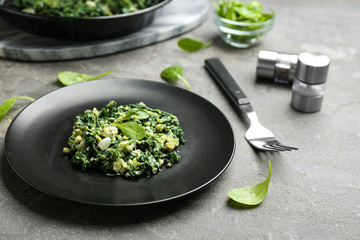 Plate with tasty spinach on grey table. Healthy food