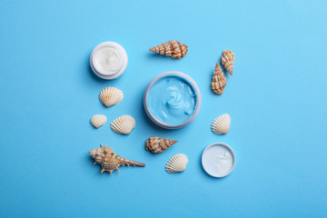 Flat lay composition with jars of body cream on light blue background