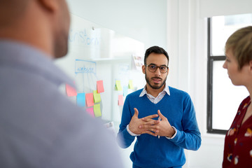 Portrait of an indian man in a diverse team of creative millennial coworkers in a startup brainstorming ideas