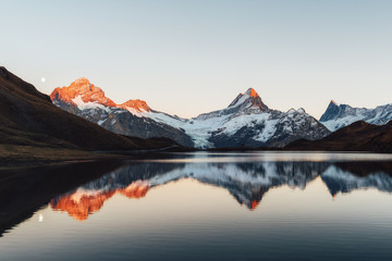 Fototapeta na wymiar Bachalpsee lake with reflection in Swiss Alps mountains. Glowing snowy peaks on background. Grindelwald valley, Switzerland. Landscape photography