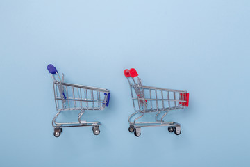 Two mini shopping carts on blue background Top view Copy space
