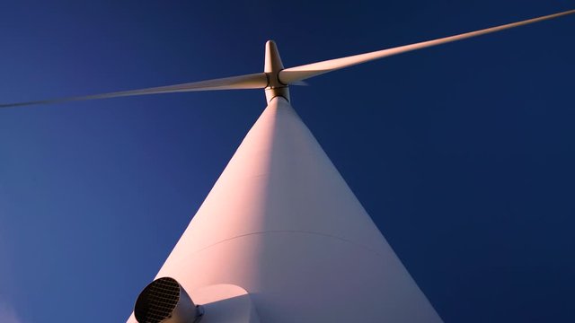 Looking directly up at a large commercial wind turbine at sunrise on a clear day