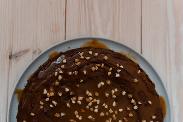 Chocolate cake with nuts. Top view delicious dark chocolate cake on the wood table. A biscuit cake is sprinkled with walnut with chocolate cream. Closeup