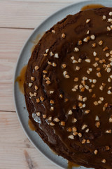 Chocolate cake with nuts. Top view delicious dark chocolate cake on the wood table. A biscuit cake is sprinkled with walnut with chocolate cream. Closeup