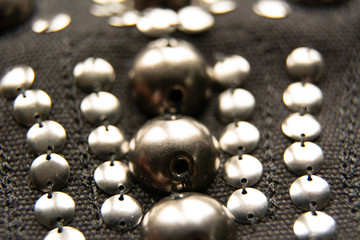 Silver shiny beads and sequins in vintage style are sewn on black coarse fabric.