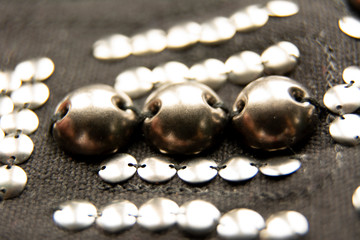 Silver shiny beads and sequins in vintage style are sewn on black coarse fabric.