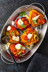 Baked stuffed bell pepper filled with minced meat, onion, tomato, and mozzarella. Dark background. Top view.