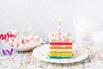 Rainbow birthday cake with marshmallows. Balls,  confetti on the festive table.