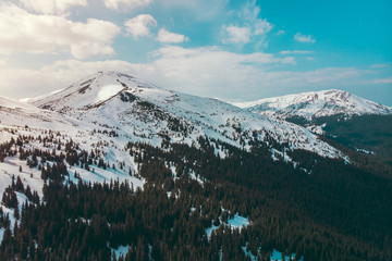 Sunny winter carpathian mountains with snow blue sky clouds shooting on quadcopter