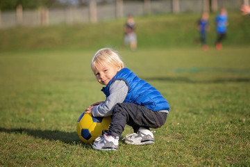 Little toddler boy, playing with soccer ball on playground in the park