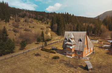 Big orange wood house in the Carpathian Mountains sunny spring day forest blue sky shooting on quadcopter