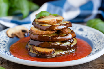 Turrets of grilled eggplants and mushrooms with tomato sauce.