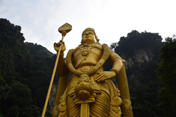 Fototapeta na wymiar Entrance to Batu Caves with the giant, golden Murugan statue and the 272-step colorful staircase