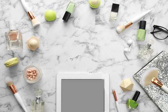 Frame made with tablet and beauty blogger's accessories on marble table, top view