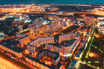 Highly populated residential area of high-rise buildings and street lighting, aerial view at night.