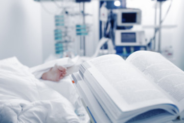 Open book on the background of a patient under 24-hour monitoring of the condition, unfocused background.