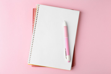 Notebooks and pen on pink background, top view