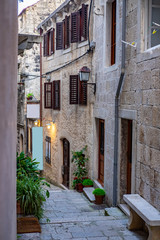 Fototapeta na wymiar Famous narrow stone street with stone houses and facades and lanterns in historic fortified Korcula town, Korcula Island, Dalmatia, Croatia