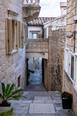 Narrow stone street with stairs, stone facades and houses with balcony in the centre of historic old town of Korcula, Korcula Island, Dalmatia, Croatia, traditional Mediterranean architecture