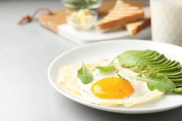 Tasty breakfast with fried egg and avocado on table, closeup