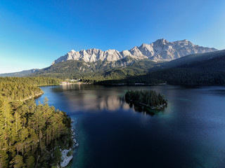 Naklejka na ściany i meble Aerial panoramic image of the Eibsee lake and Zugspitze mountain with blue sky