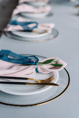Luxury wedding table service with blue tablecloth and gentle pink napkins