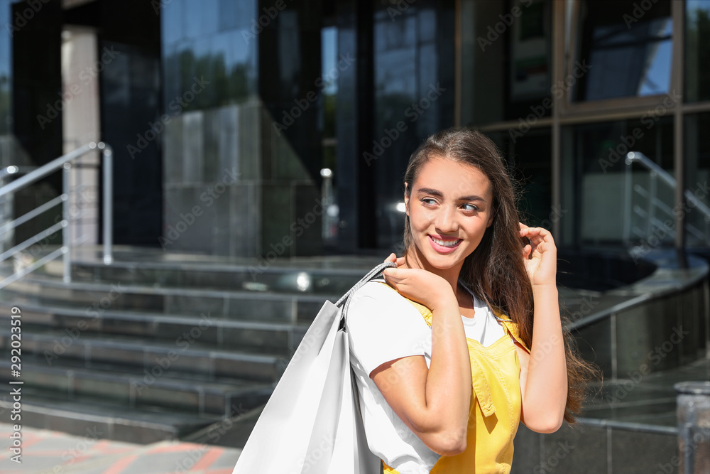 Poster Happy young woman with shopping bags outdoors