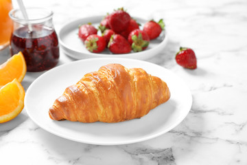 Tasty breakfast with croissant served on white marble table
