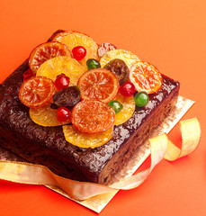 Fruit Cake, decorated with Glaced Fruit on board against red background