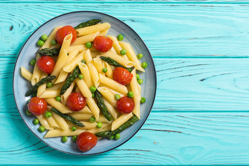 Penne pasta salad with asparagus , tomatoes and peas