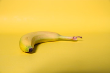 Banana on yellow background, with slight shadow. Single banana.