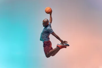 Poster Slam dunk. Full length of young african backetball player jumping against colorful background © Friends Stock