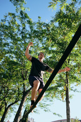 Man Training With Trickline Slackline In City Park