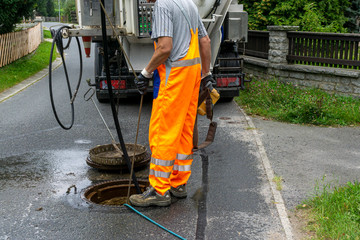 sewerage worker on street cleaning pipe