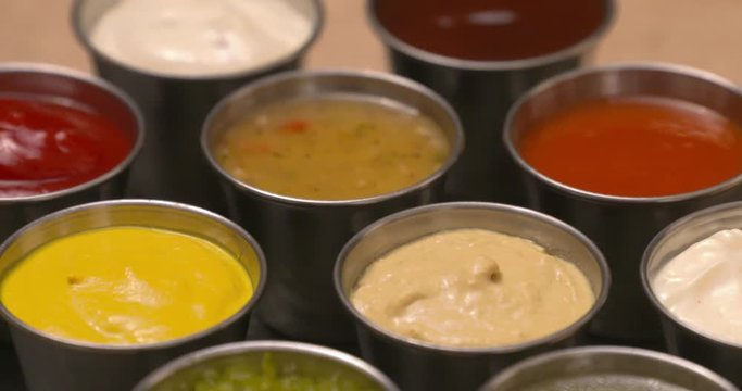 Close-up selection of condiments, dips, and sauces laid out on a slate serving board.