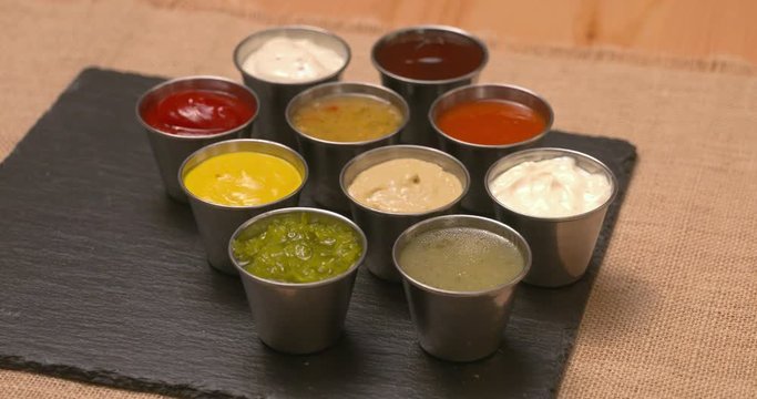 Selection of condiments, dips, and sauces laid out on a slate serving platter.