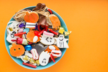 Halloween Jack o Lantern candy bowl with candy and halloween cookies Trick or Treat on orange background