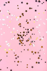 Golden and silver stars on pink pastel background. Flat lay, top view.