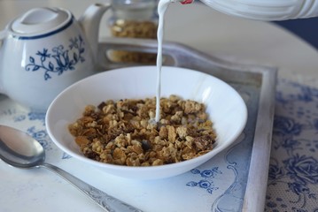 Pouring milk to a bowl full of cereals and chocolate muesli
