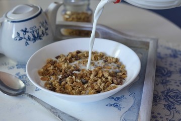 Pouring milk to a bowl full of cereals and chocolate muesli